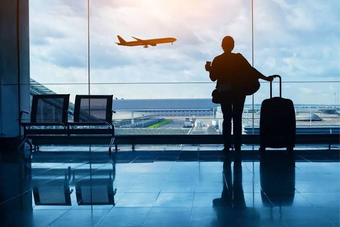 Traveler waiting at the airport with a flight overhead